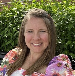 Professional woman smiling outdoors in natural greenery for corporate and business branding.