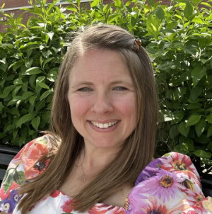 Professional woman smiling outdoors in natural greenery for corporate and business branding.