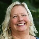 Experienced woman smiling outdoors, professional headshot for consulting services.