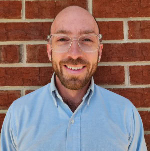 Professional business consultant smiling in front of brick wall, CTLG branding.