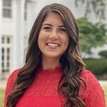 Professional woman smiling outdoors, business casual attire, urban background.