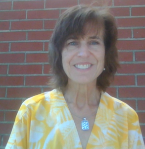 Empowered woman smiling outdoors in yellow floral blouse promoting leadership and consulting services.